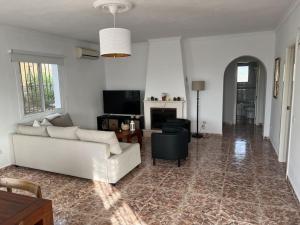 - un salon avec un canapé blanc et une télévision dans l'établissement Casa del Barco with pool and stunning views, à Guaro