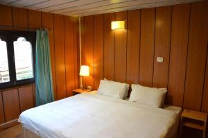 帕羅的住宿－Sinchula Villa，卧室配有一张白色大床和木墙