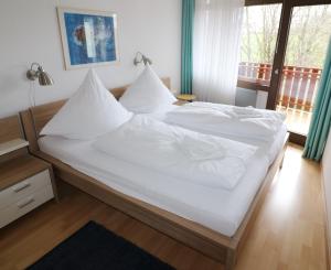 a bed with white sheets and pillows in a bedroom at Kurhotel Schluchsee App 2313 - Genießer-Apartment mit Südbalkon - mit Indoorpool Schluchsee, Hochschwarzwaldkarte in Schluchsee