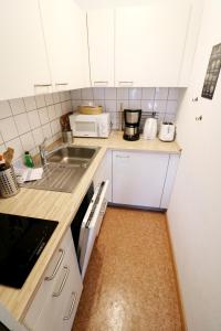 a small kitchen with white cabinets and a sink at Kurhotel Schluchsee App 2313 - Genießer-Apartment mit Südbalkon - mit Indoorpool Schluchsee, Hochschwarzwaldkarte in Schluchsee