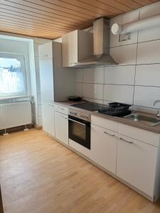 La cuisine est équipée de placards blancs et d'un four avec plaques de cuisson. dans l'établissement Ferienwohnung Montuerwohnung Naila, à Naila