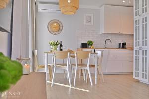 eine Küche mit weißen Schränken sowie einem Tisch und Stühlen in der Unterkunft Sunset Apartments - Roosevelta - Premium - Garaż in Świnoujście