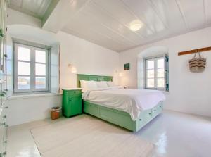 um quarto com uma cama com paredes e janelas brancas em Hydra Homesteads em Hidra