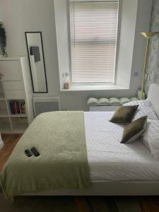 um quarto com uma cama com duas almofadas e uma janela em The Wee Studio Flat em Paisley