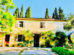 a large yellow house with trees in front of it at La Maison M 6pers in Valréas