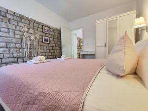 a bedroom with a pink bed with a brick wall at Apartments Vodaric in Cres