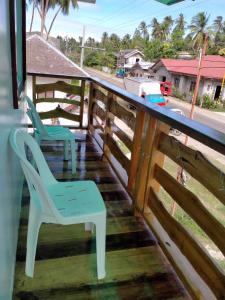 2 chaises assises sur une terrasse couverte avec une clôture dans l'établissement Beachfront Guesthouse Siquijor, à San Juan