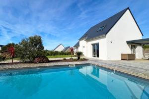 a house with a swimming pool in front of a house at Villa avec piscine privée, sauna, jardin et parking in Barneville-Carteret