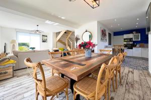 cocina y sala de estar con mesa de madera y sillas en Villa avec piscine privée, sauna, jardin et parking, en Barneville-Carteret