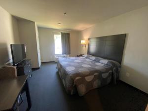 a hotel room with a bed and a flat screen tv at Savannah Suites Atlanta Airport in Atlanta