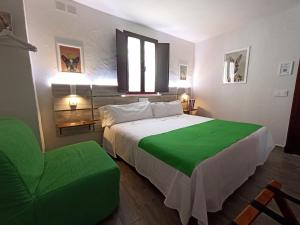 a bedroom with a large bed and a green chair at LA JARANA Casa Hotel in Zahara de la Sierra