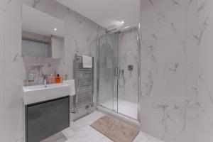 a white bathroom with a shower and a sink at Stylish Spacious Retreat Luxury 2 Bedroom Haven 2 in London