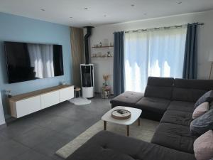 sala de estar con sofá y TV de pantalla plana en Loue maison pour les 24h du Mans, en Mulsanne