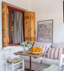 sala de estar con sofá y mesa con naranjas. en Η αυλή της Ασπασίας, Χανιά Κρήτη, en Lákkoi