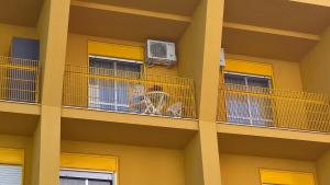 un edificio con balconi con sedie e aria condizionata di YELLOW HOUSE a Cefalù Altre 3 foto