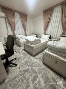 a room with three beds and a chair and a desk at MiCasa Family Guesthouse in Tashkent