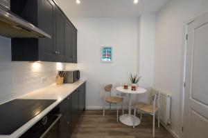 a kitchen with black cabinets and a small table at Surf Cottage in Cromer