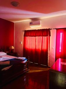 um quarto vermelho com uma cama e uma janela com cortinas vermelhas em Casa BB&Djassi em Ponta do Sol