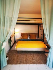 a bedroom with a bed with yellow sheets and blue curtains at Villa accès port plage à pied sanary sur mer in Sanary-sur-Mer