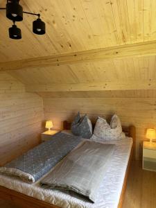łóżko w drewnianym pokoju z 2 lampami w obiekcie Chatki nad wodnym zakątkiem. w mieście Wapnica