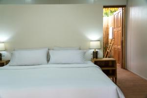 1 dormitorio con 1 cama blanca grande y 2 lámparas en Sumba Retreat Kerewe, en Waikabubak