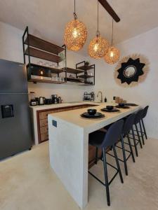 a kitchen with a island with chairs and a refrigerator at Little Oasis with private pool in the jungle in Chemuyil