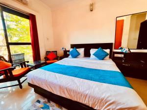 a bedroom with a large bed with blue pillows at Hamilton Hotel & Resort Goa in Goa