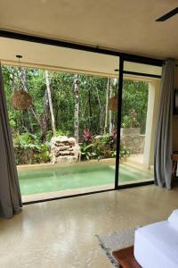 a room with a large sliding glass door to a garden at Little Oasis with private pool in the jungle in Chemuyil