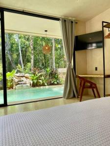 a bedroom with a bed and a view of a pool at Little Oasis with private pool in the jungle in Chemuyil