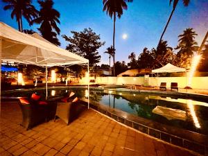 a swimming pool with chairs next to a resort at Hamilton Hotel & Resort Goa in Goa