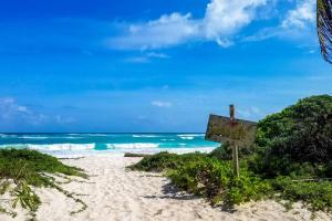 a sign on the beach in front of the ocean at Little Oasis with private pool in the jungle in Chemuyil
