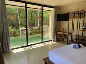 a bedroom with a bed and a large glass window at Little Oasis with private pool in the jungle in Chemuyil