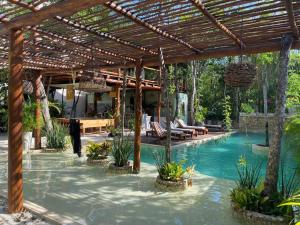 a swimming pool with a wooden pergola and a resort at Little Oasis with private pool in the jungle in Chemuyil
