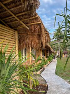 une personne marchant sur un chemin à côté d'une cabane dans l'établissement Sumba Retreat Kerewe, à Waikabubak