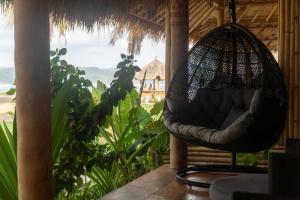 a swing hanging from a porch with a view of the ocean at Sumba Retreat Kerewe in Waikabubak