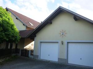 a white house with two garage doors and a clock at Colourful 2.5 Bedroom With Large Balcony & Garden. in Prinzersdorf