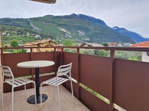 balcón con mesa, sillas y montaña en Conca d'oro B&B and Apartments, en Nago-Torbole