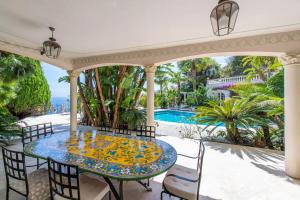 Un patio con mesa y sillas y una piscina. en Villa de luxe à Cap-d'Ail, en Saint-Antoine