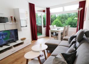 a living room with a couch and a tv and a table at Kurhotel Schluchsee App 1321 - Schwarzwälder Kirsch - mit Indoorpool, Schluchsee in Schluchsee