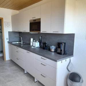 a kitchen with white cabinets and a black counter top at Bichlhof Bärfra Ferienwohnung Hunsrück in Morbach +24 photos