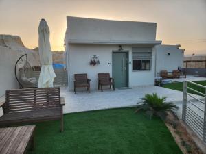 une terrasse avec un banc et un parasol dans l'établissement בצל ההר, à Ein Tamar 