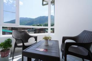 einen Balkon mit einem Tisch, Stühlen und Fenstern in der Unterkunft Hotel Kullu Valley in Kulu