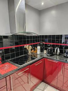 eine Küche mit roten Schränken und schwarzen Wandfliesen in der Unterkunft Maison de 2 chambres a Ver sur Mer a 100 m de la plage avec jardin clos et wifi in Ver-sur-Mer