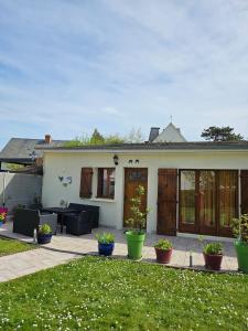 ein Haus mit einer Terrasse mit Pflanzen im Hof in der Unterkunft Maison de 2 chambres a Ver sur Mer a 100 m de la plage avec jardin clos et wifi in Ver-sur-Mer
