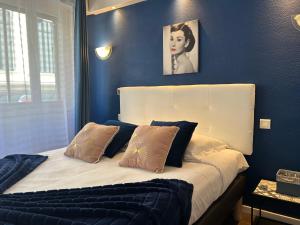 a blue bedroom with a bed with two pillows at ATH hôtel Athénée in Cannes
