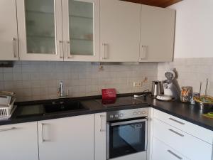 cocina con armarios blancos y fogones en Fewo Turmblick, en Oberried