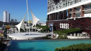 a swimming pool in front of a building with a sail boat at The Coast in Bangkok