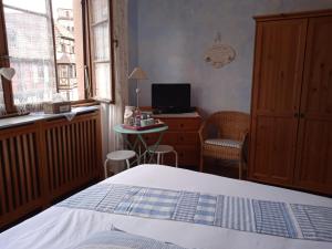 a bedroom with a bed and a desk with a computer at Appartements & Chambres Les Loges du Capucin in Kaysersberg