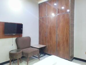 um quarto com uma cadeira, uma televisão e um armário em Dove Inn Family Residency Johar Town em Lahore