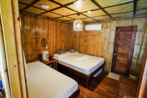 two beds in a small room with wooden walls at Marika Resort in Badian